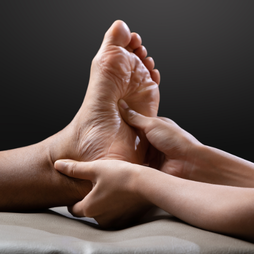 Gros plan d'un thérapeute effectuant de la réflexologie plantaire sur un pied