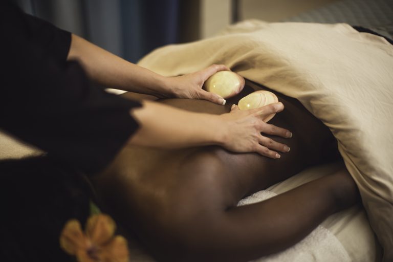 Mains de thérapeutes effectuant un massage à l'aide de coquillages