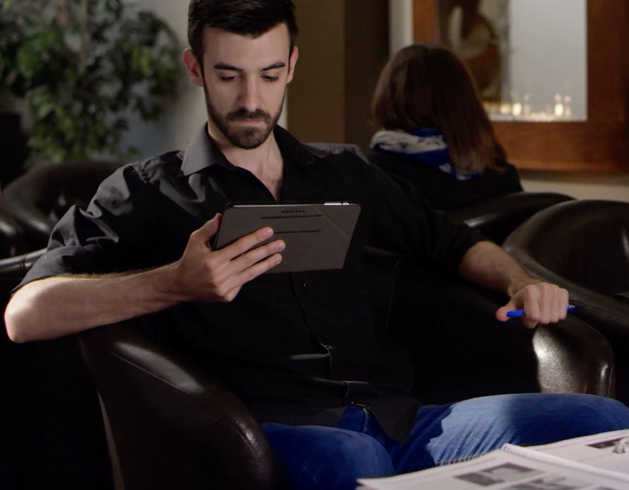 Jeune homme assis dans un fauteuil regardant une tablette électronique